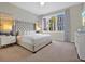 Cozy bedroom featuring a tufted headboard, soft lighting, and a large window at 7770 Sandy Ridge Dr # 117, Reunion, FL 34747