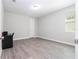 A clean bedroom with gray wood-look floors, neutral walls, a bright window, and a desk at 8066 Ludington Cir, Orlando, FL 32836