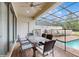 Outdoor patio with a dining table and chairs under a screened enclosure by the pool at 8806 Geneve Ct, Kissimmee, FL 34747