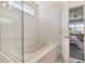 This bathroom features a soaking tub with glass doors and a window, offering a bright and tranquil space at 965 Maypole Dr, Apopka, FL 32703