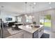 Bright kitchen with white cabinets, stainless steel appliances, island seating, and open access to the living area and backyard at 965 Maypole Dr, Apopka, FL 32703