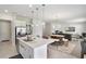 Open-concept kitchen with white cabinets, stainless steel appliances, island seating, and a view into the living area at 965 Maypole Dr, Apopka, FL 32703