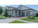 Inviting home showcasing a manicured lawn and gray exterior, complete with a two-car garage and covered porch at 9863 Summerlake Groves St, Winter Garden, FL 34787