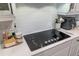 Close-up of kitchen cooktop and white cabinets with a stylish subway tile backsplash at 9863 Summerlake Groves St, Winter Garden, FL 34787