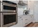 Close-up of stainless-steel double ovens and cooktop in a modern kitchen with white cabinets at 9863 Summerlake Groves St, Winter Garden, FL 34787