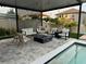 Stylish outdoor lounge area under a pergola, featuring comfortable seating, a fire pit, and a view of the pool at 9863 Summerlake Groves St, Winter Garden, FL 34787
