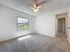 A cozy bedroom with a ceiling fan, plush carpeting, and a view of the outdoors through the window at 10018 Chesham Dr, Orlando, FL 32817