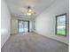 A spacious carpeted bedroom with a ceiling fan, and a glass door leading to the outside at 10018 Chesham Dr, Orlando, FL 32817
