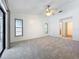 A spacious carpeted bedroom with a ceiling fan, two windows, and a glass door at 10018 Chesham Dr, Orlando, FL 32817