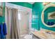 Bright bathroom featuring a teal wall, a round mirror, and a tub-shower combo with a gray shower curtain at 109 Woodfield Ct, Sanford, FL 32773