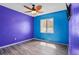 Colorful bedroom featuring vibrant purple and blue walls, a window, and wood-look flooring at 109 Woodfield Ct, Sanford, FL 32773