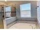 Bathroom showcasing a soaking tub with tile surround, glass-enclosed shower, and a bright window with privacy blinds at 11070 Longleaf Woods Dr, Orlando, FL 32832