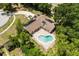 Overhead view of a solar-paneled home featuring a kidney-shaped pool and set amid lush landscaping and a circular driveway at 12 Horseman Cv, Longwood, FL 32750
