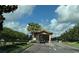 Community entrance gate with palm trees and well-manicured landscaping under a bright, partly cloudy sky at 1269 Long Cove Loop # 1269, Davenport, FL 33896