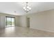 Spacious living area with tile floors, a contemporary light fixture, and a sliding glass door to the balcony at 1269 Long Cove Loop # 1269, Davenport, FL 33896