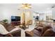 Open-concept living room with hardwood-style flooring, comfortable seating, and a large television at 1400 Holly Glen Run, Apopka, FL 32703