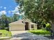 Traditional house with manicured lawn, mature trees, and attached two-car garage at 14715 Buckingham Gate Ct, Orlando, FL 32828