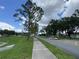Manicured community lawns with paved sidewalks and green trees underneath blue skies and fluffy white clouds at 164 Royal Palm Dr, Leesburg, FL 34748