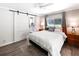 Cozy bedroom with king-size bed, sliding barn door, and serene decor; bathroom visible through door at 164 Royal Palm Dr, Leesburg, FL 34748