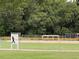 A clear sign indicates that this green and fenced area is in fact, a softball field surrounded by trees at 164 Royal Palm Dr, Leesburg, FL 34748