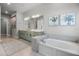 Serene bathroom with a soaking tub, neutral tile, and modern fixtures at 17290 Hickory Wind Dr, Clermont, FL 34711