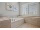 Relaxing bathroom with a tiled tub, neutral color scheme, and plenty of natural light at 17290 Hickory Wind Dr, Clermont, FL 34711