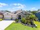 Landscaped home featuring stone accents, lush greenery, and a spacious three-car garage, perfect for any Gathering at 17290 Hickory Wind Dr, Clermont, FL 34711