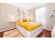 Bright bedroom featuring hardwood floors, a yellow platform bed, and sconce lighting creating a cozy and stylish space at 1785 Rushden Dr, Ocoee, FL 34761