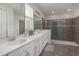 Modern bathroom featuring a double vanity, large mirror, tiled shower with glass enclosure, and neutral color palette at 1811 Caribbean View Ter, Kissimmee, FL 34747