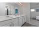 Bathroom with double vanity, white countertops, and a mirror reflecting into a bedroom with blue walls at 1811 Caribbean View Ter, Kissimmee, FL 34747