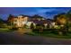 Elegant home with lush landscaping, a circular driveway, and a secure gated entrance at dusk at 2211 Azalea Pl, Winter Park, FL 32789