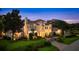 Elegant home with lush landscaping, a circular driveway, and a secure gated entrance at twilight at 2211 Azalea Pl, Winter Park, FL 32789