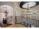 Elegant home foyer with curved staircase, ornate iron railings, and decorative chandeliers at 2211 Azalea Pl, Winter Park, FL 32789