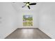 Empty bedroom with gray laminate flooring, ceiling fan, and a window with a view to the neighborhood at 3 Pine Glen Dr, Debary, FL 32713
