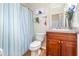 Well-lit bathroom features a wood vanity, a toilet, and a blue-and-white striped shower curtain at 30308 Cheval St, Mount Dora, FL 32757