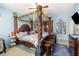 Bedroom with unique four poster bed with decorative carvings, blue painted walls and carpet, and a toddler crib at 30308 Cheval St, Mount Dora, FL 32757