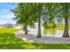 Lakeside view with a sandy beach, mature trees, and a private dock with covered seating in the background at 5005 Shore Side Dr, Lakeland, FL 33812
