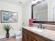 Well-lit bathroom with a granite countertop, a decorative mirror, and a wooden vanity at 533 Mount Olympus Blvd, New Smyrna Beach, FL 32168