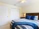 Comfortable bedroom features neutral walls, ceiling fan, closet, and a bed with blue and grey striped comforter at 533 Mount Olympus Blvd, New Smyrna Beach, FL 32168