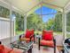 Enclosed lanai featuring outdoor seating with bright orange cushions and views of the landscaped backyard at 533 Mount Olympus Blvd, New Smyrna Beach, FL 32168