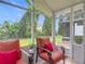 Enclosed lanai featuring outdoor seating with bright orange cushions and views of the lushly landscaped backyard at 533 Mount Olympus Blvd, New Smyrna Beach, FL 32168