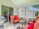 Enclosed lanai featuring outdoor seating with bright orange cushions and views of the lushly landscaped backyard at 533 Mount Olympus Blvd, New Smyrna Beach, FL 32168