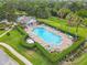 Aerial view of the community pool with chairs, tables, trimmed hedges, palm trees and a pool house at 533 Mount Olympus Blvd, New Smyrna Beach, FL 32168