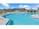 Community swimming pool with lounge chairs, umbrellas, and a covered pool house on a sunny day at 7538 Headwaters Ct, Groveland, FL 34736
