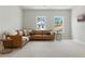 Bright bonus room featuring a comfortable leather sectional sofa, stylish side tables and two bright windows at 7613 Wandering Way, Orlando, FL 32836