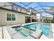 A screened-in pool and hot tub sit adjacent to the home with lounge chairs and shade at 7613 Wandering Way, Orlando, FL 32836