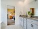 Bright bathroom featuring granite countertops, white cabinets, tile flooring, and a doorway to the main bedroom at 9426 Launch Point Rd, Orlando, FL 32832