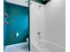 A modern bathroom with a white tiled shower/tub combination with a teal accent wall at 9426 Launch Point Rd, Orlando, FL 32832