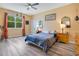 Warm bedroom with a ceiling fan, bright window, hardwood floors, and a comfortable king-sized bed at 9426 Launch Point Rd, Orlando, FL 32832