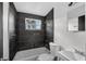 Modern bathroom featuring black tile, a white toilet, a white tub, and vanity at 1257 N Pine Hills Rd, Orlando, FL 32808